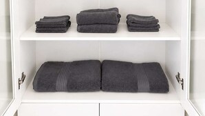 Une armoire blanche dotée de nombreuses étagères, dont certaines contiennent des serviettes pliées et d’autres des bocaux.