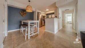 A modern kitchen with white cabinetry, a stainless steel refrigerator, and a hanging light fixture. - Blue Dolphin - 5 minutes from the beach and close to everything! (Destin)