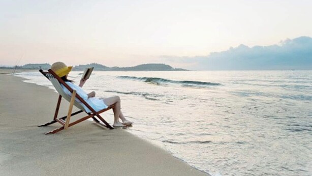 A beach with a single lounge chair and a person reading a book. - Blue Dolphin - 5 minutes from the beach and close to everything! (Destin)