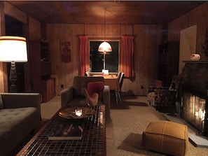 Uma sala de estar acolhedora, com lareira, mesa de jantar e assentos confortáveis.