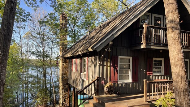 A rustic cabin with a stone chimney, wooden exterior, and a balcony overlooking a lake. - Lakefront cabin in quiet cove on Lake Hartwell (Hartwell)