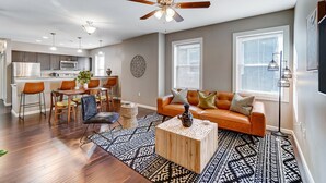 A modern living room with a sofa, coffee table, and a dining area with chairs and a table. - Walkable to Oakley Square-Newly Renovated-King Bed (Cincinnati)
