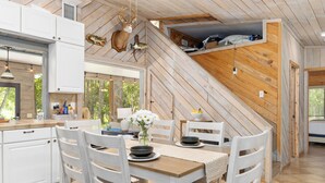 A modern kitchen with white cabinets, a wooden dining table, and a view of the outdoors. - Beautiful secluded setting on the Rainbow River surrounded by state forest (Dunnellon)