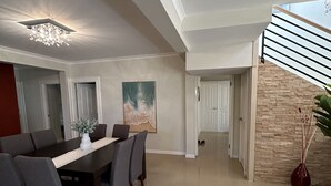 Un comedor amplio con una mesa larga y sillas, una araña y un cuadro en la pared.