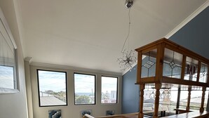 Una cocina con barra de madera, una escalera y amplios ventanales con vistas al exterior.