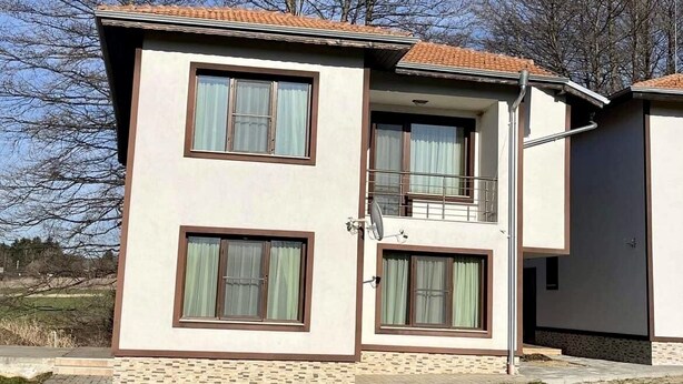 Een gebouw met twee verdiepingen, voorzien van een pannendak, grote ramen en een schotelantenne.