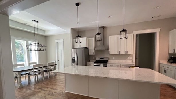 Una cocina moderna con una isla grande, luces colgantes y suelo de madera.