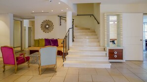 Amplia sala de estar con una escalera, un sofá con cojines de colores y una mesa de centro de madera.