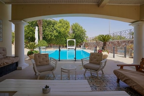 A poolside area with a pool, lounge chairs, and a covered seating area.