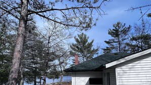 A cabin with a wooden deck, surrounded by trees and a lake. - Historic but HiTech, modern Burleigh Falls cottage on Stony Lake. Amazing views (Harcourt)