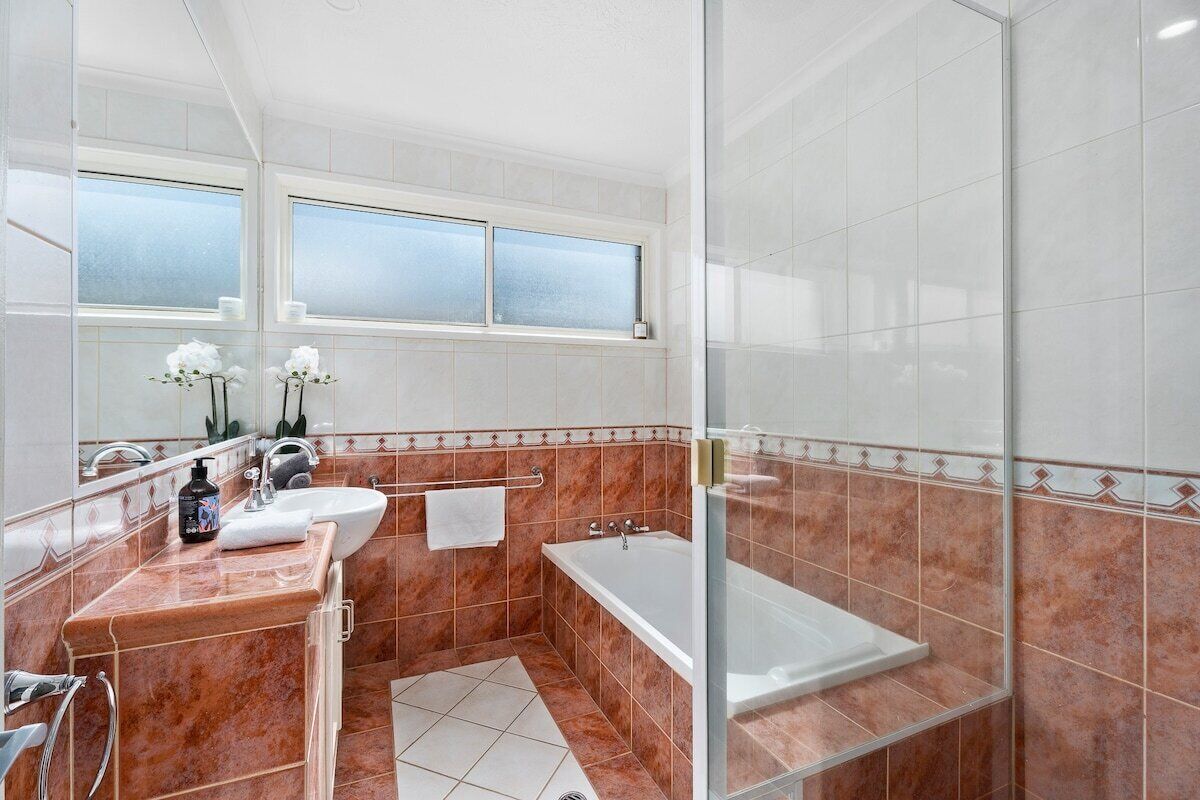 Een moderne badkamer met een douchecabine van glas, een badkuip en een wastafelmeubel met een wastafel en spiegel.