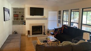 A living room with a fireplace, a sofa, a coffee table, and a TV mounted on the wall. - Dataw Island Golf Villa (Saint Helena Island)