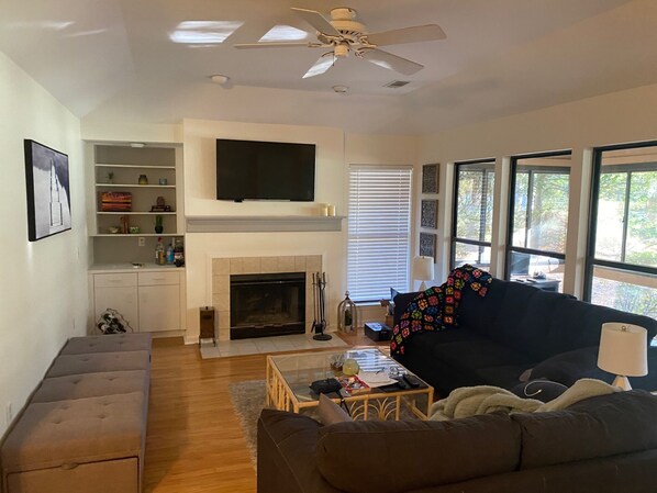 Una sala de estar con chimenea, un sofá, una mesa de centro y un televisor montado en la pared.