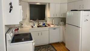 A compact kitchen with white cabinets, a built-in oven, a sink, and a refrigerator. - Dataw Island Golf Villa (Saint Helena Island)