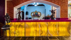 Un comptoir d’accueil avec un revêtement en marbre, une arche en briques et des statues.