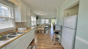 Une cuisine avec des armoires blanches, un plan de travail en bois, un évier et un réfrigérateur.