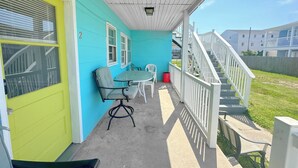 Un espace extérieur abrité, équipé d’une table et de chaises, d’un escalier et offrant une vue sur les bâtiments voisins.
