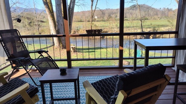 A covered outdoor seating area with a view of a river and trees. - Riverfront Romantic Getaway (Andrews)