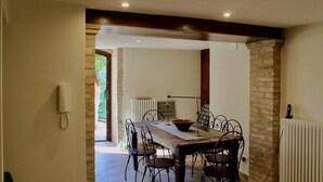 A dining area with a wooden table and chairs, a radiator, and a telephone on the wall.