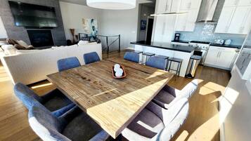 A modern kitchen with white cabinets, a large island, and a dining area with a wooden table and blue chairs.