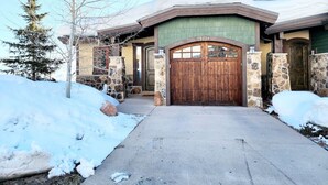 A snow-covered house with a stone facade, a wooden front door, and a chimney. - Best View on Fairway, With ready Hot Tub! (Park City)