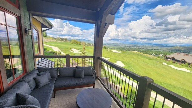 A balcony with a sofa and round table, overlooking a golf course. - Best View on Fairway, With ready Hot Tub! (Park City)