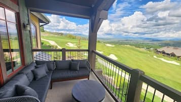 A balcony with a sofa and round table, overlooking a golf course.