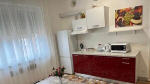 A compact kitchen with a microwave, kettle, and a fruit painting on the wall. - Le Maschere  (Mestre)