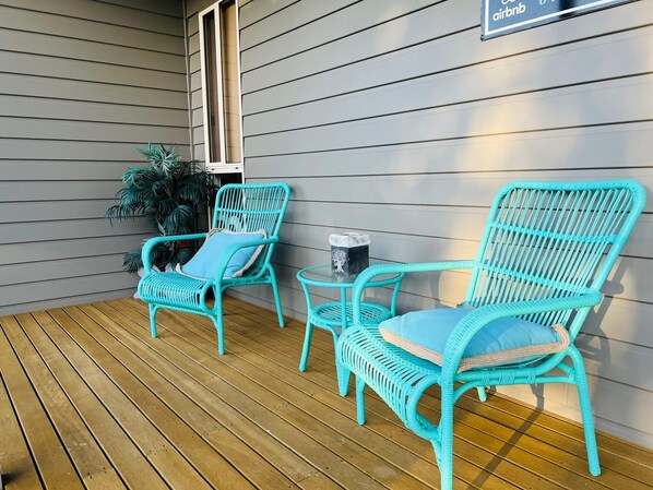 A covered porch with two turquoise wicker chairs and a small table, a potted plant, and a sign for Airbnb. - The Four CCCC's - WI FI (Robe)