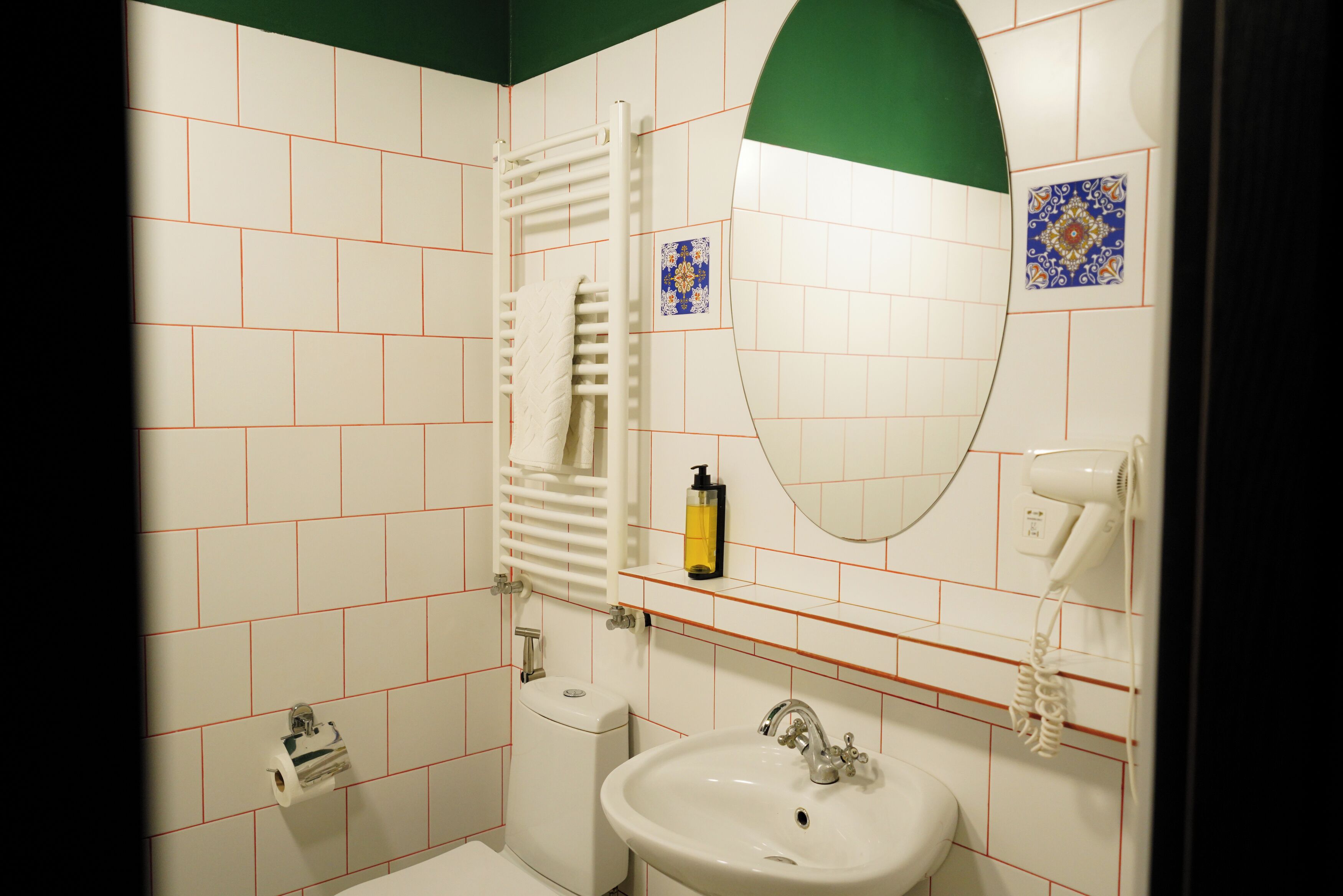 A bathroom with a white sink, a mirror, a towel rack, a toilet, and a hairdryer.