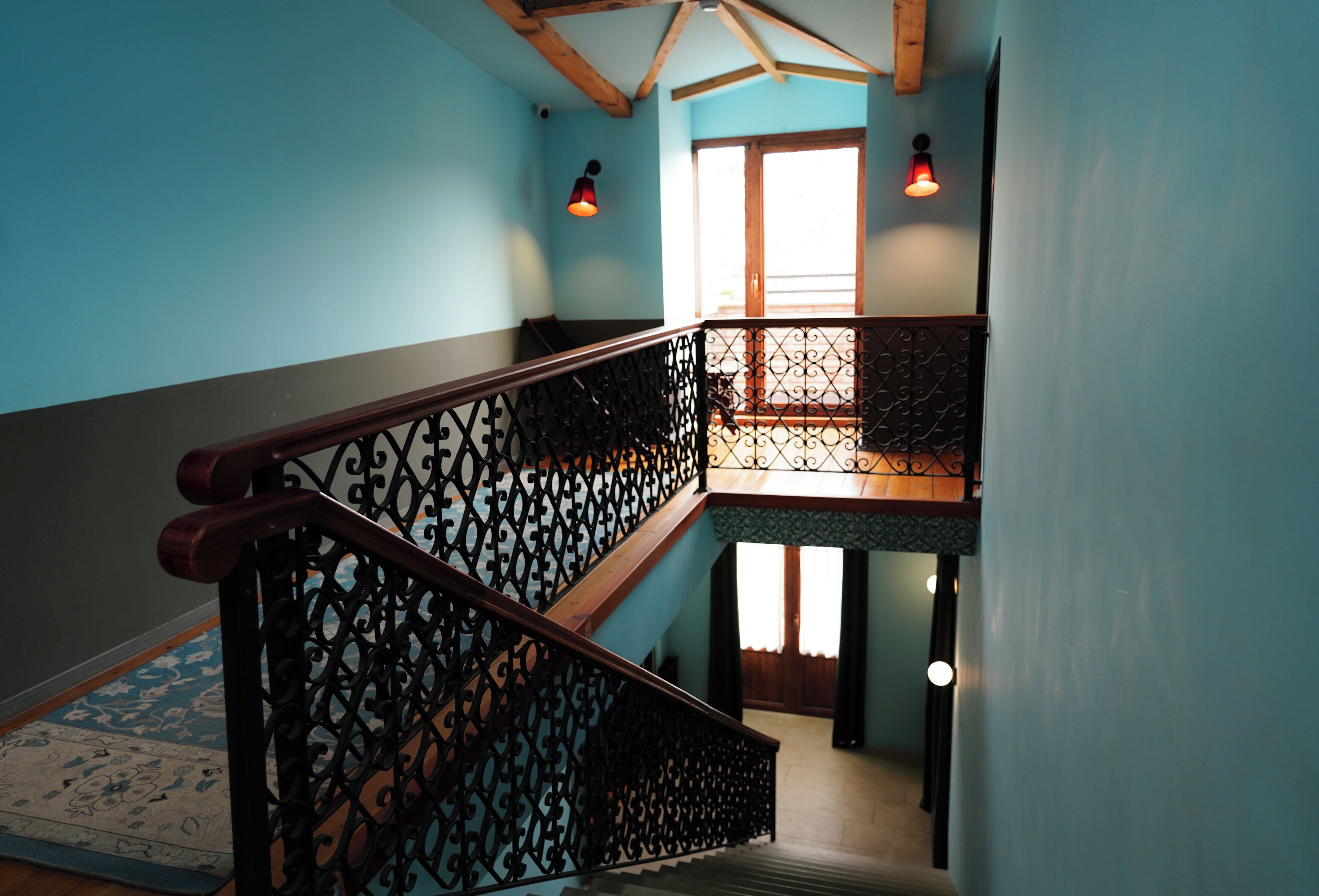 Un escalier orné de rampes en métal et de mains courantes en bois, menant à l’étage supérieur.