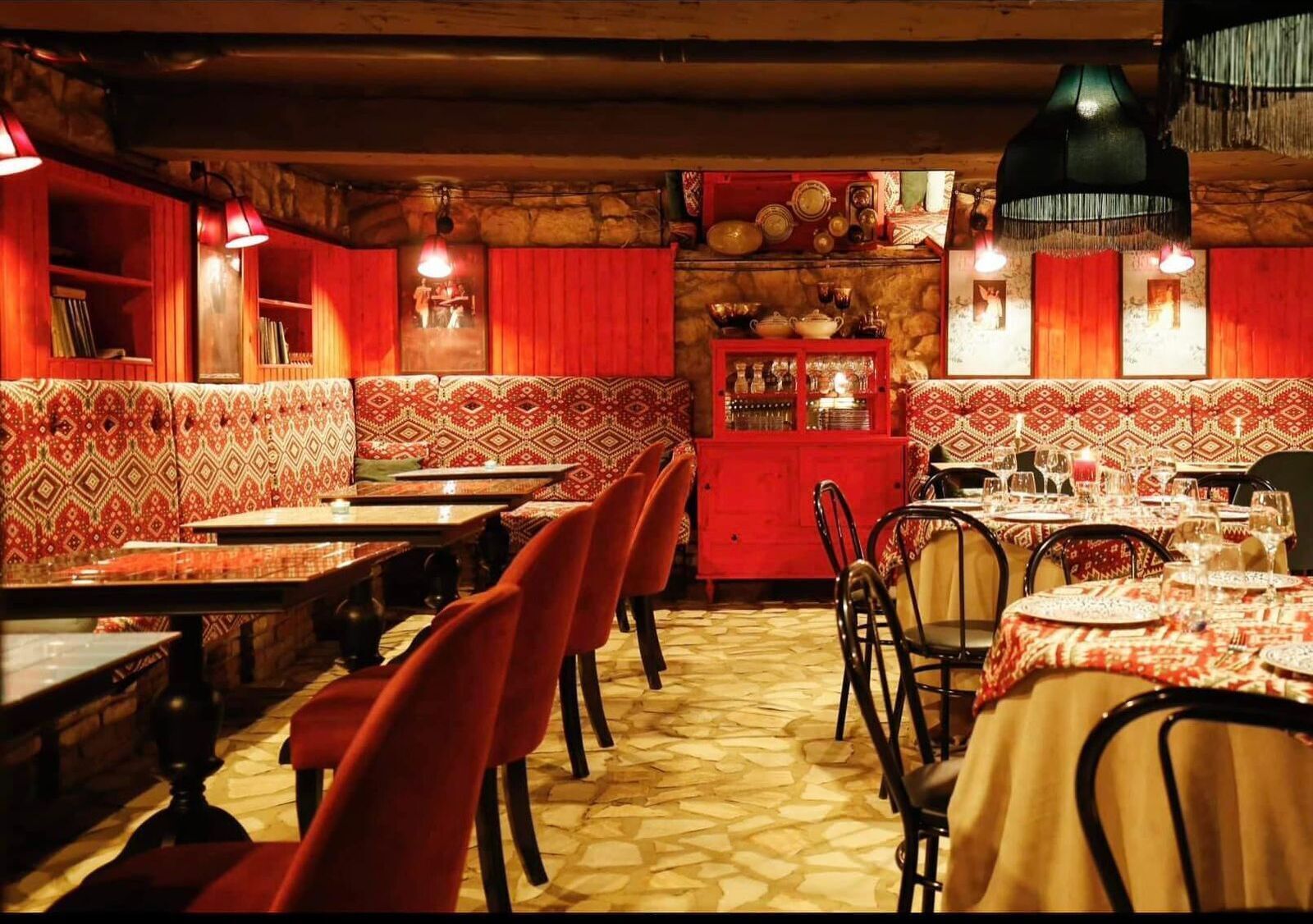 A restaurant with red booths, tables set for dining, and a patterned floor.
