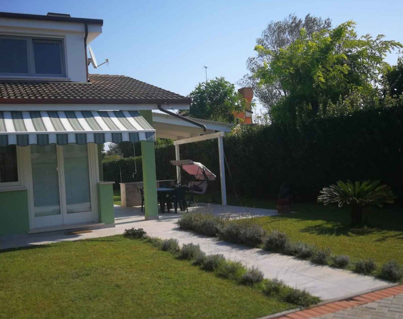 A house with a covered patio area, a small garden, and a satellite dish.
