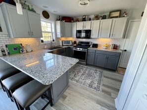 A kitchen with a granite countertop, stainless steel appliances, and a large island with bar stools. - Cozy 4 Bedroom 3 Bath, 3 miles from PSU campus/downtown in quiet neighborhood  (State College)