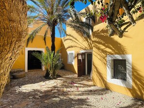 A courtyard with palm trees, a stone floor, and yellow walls. - Ibiza-Peacefull Villa with Pool near Ibiza (Santa Eularia del Rio)