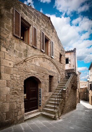 Un bâtiment en pierre avec une porte en bois sombre, un escalier et une enseigne sur laquelle on peut lire « ANTICHITA ».