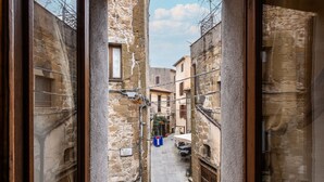 Une ruelle étroite bordée d’immeubles en pierre, un carrefour en T et un panneau indiquant un espace public.