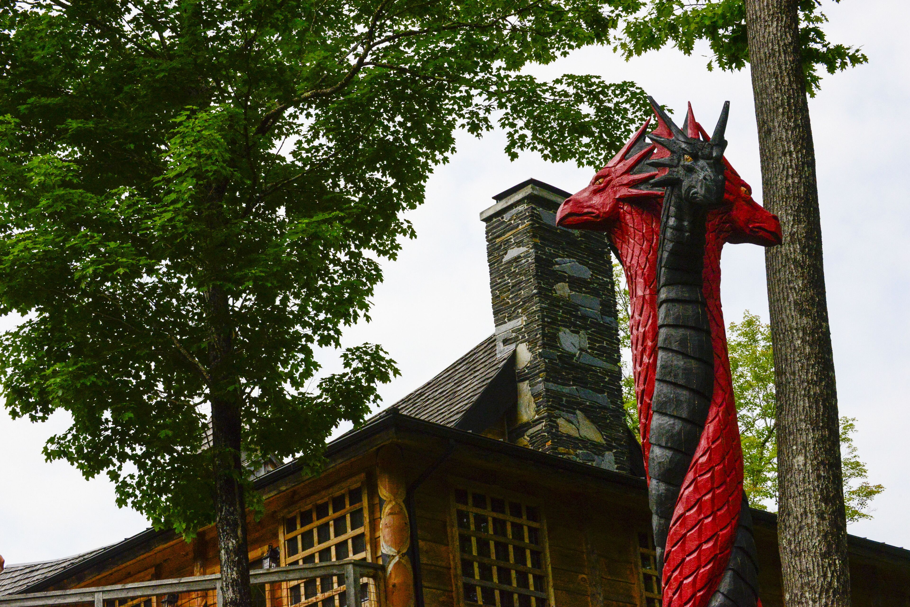 Un edificio con una chimenea de piedra y una escultura de dragón rojo.