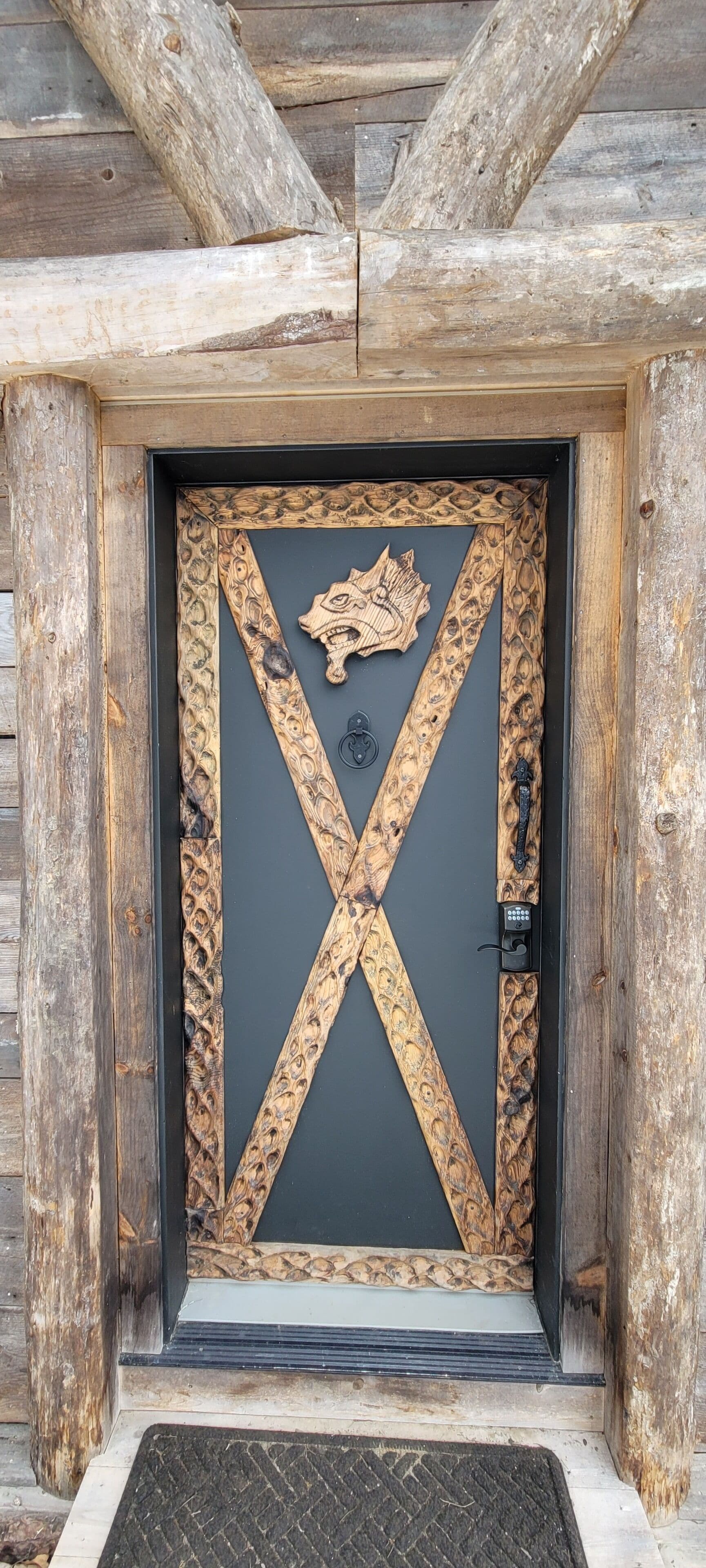Une porte en bois ornée de sculptures complexes et dotée d’une poignée en métal.