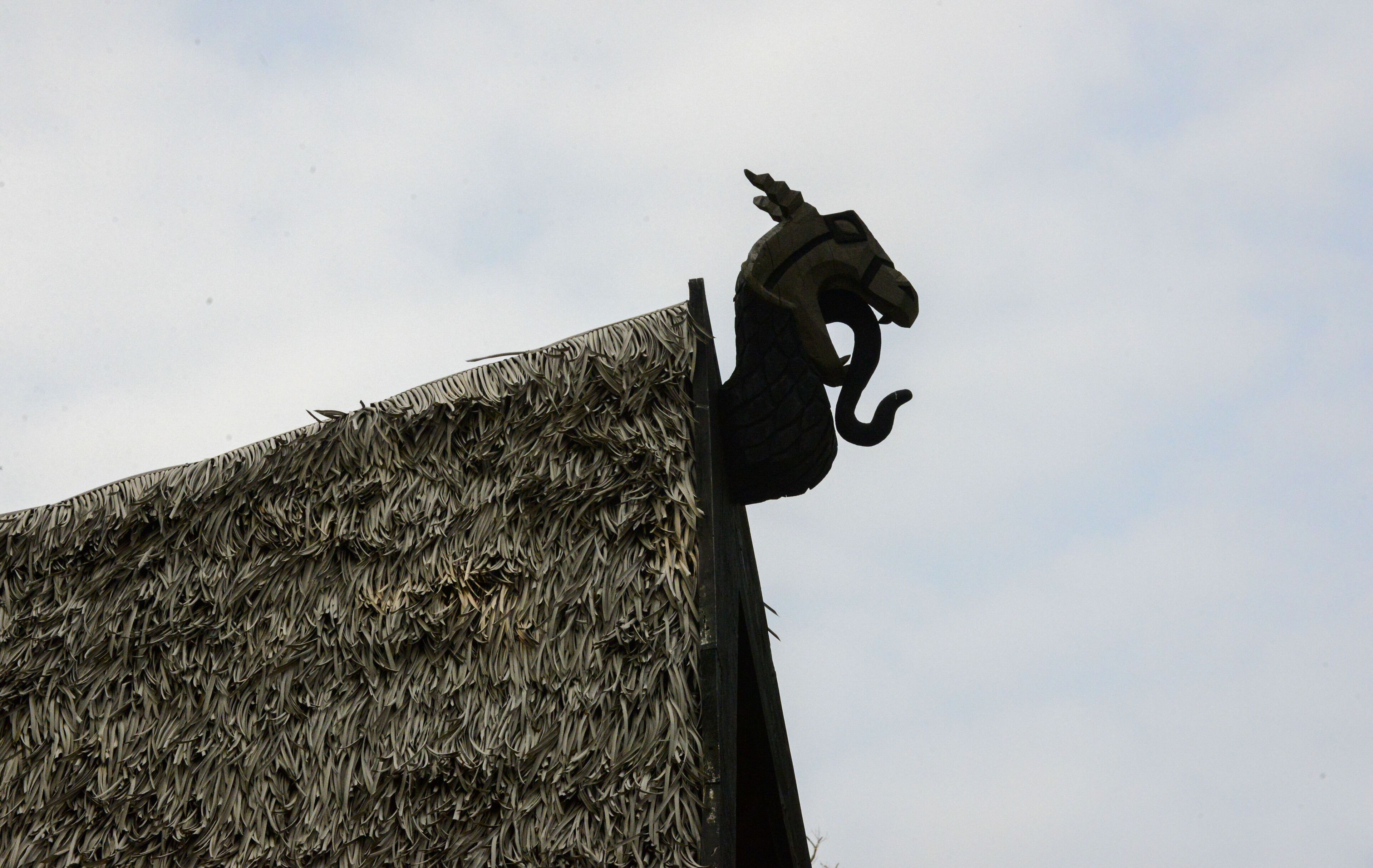 A thatched roof structure with a decorative metal sculpture.