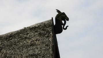 A thatched roof structure with a decorative metal sculpture.