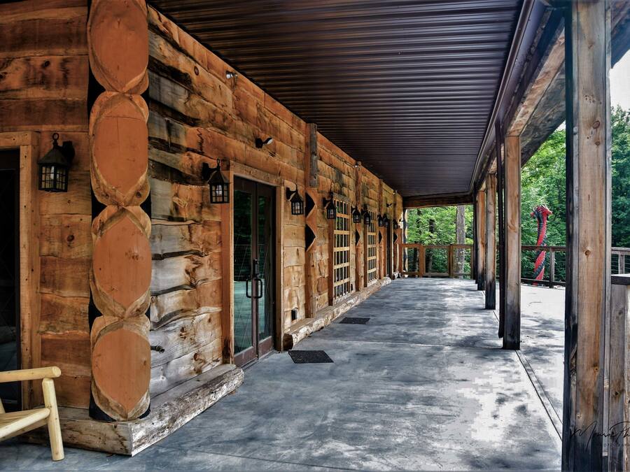 A log cabin with a covered porch, wooden benches, and lanterns.
