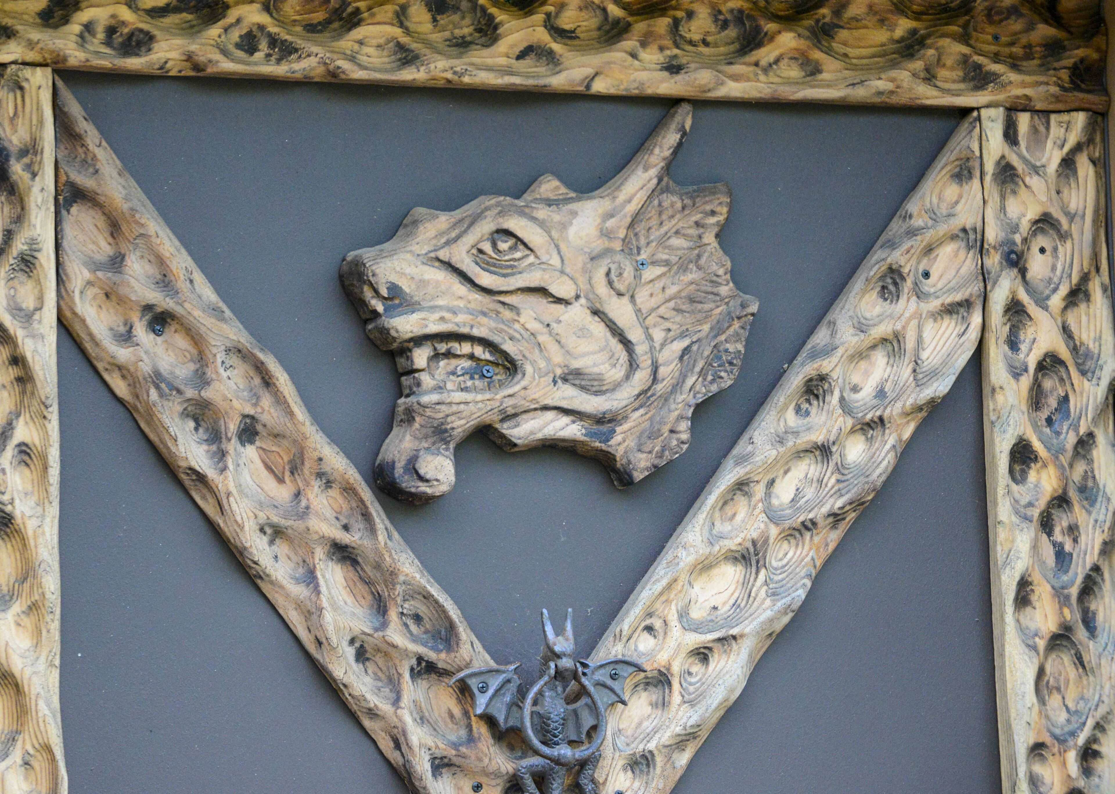 A carved wooden head with a wolf's face, surrounded by a geometric frame.