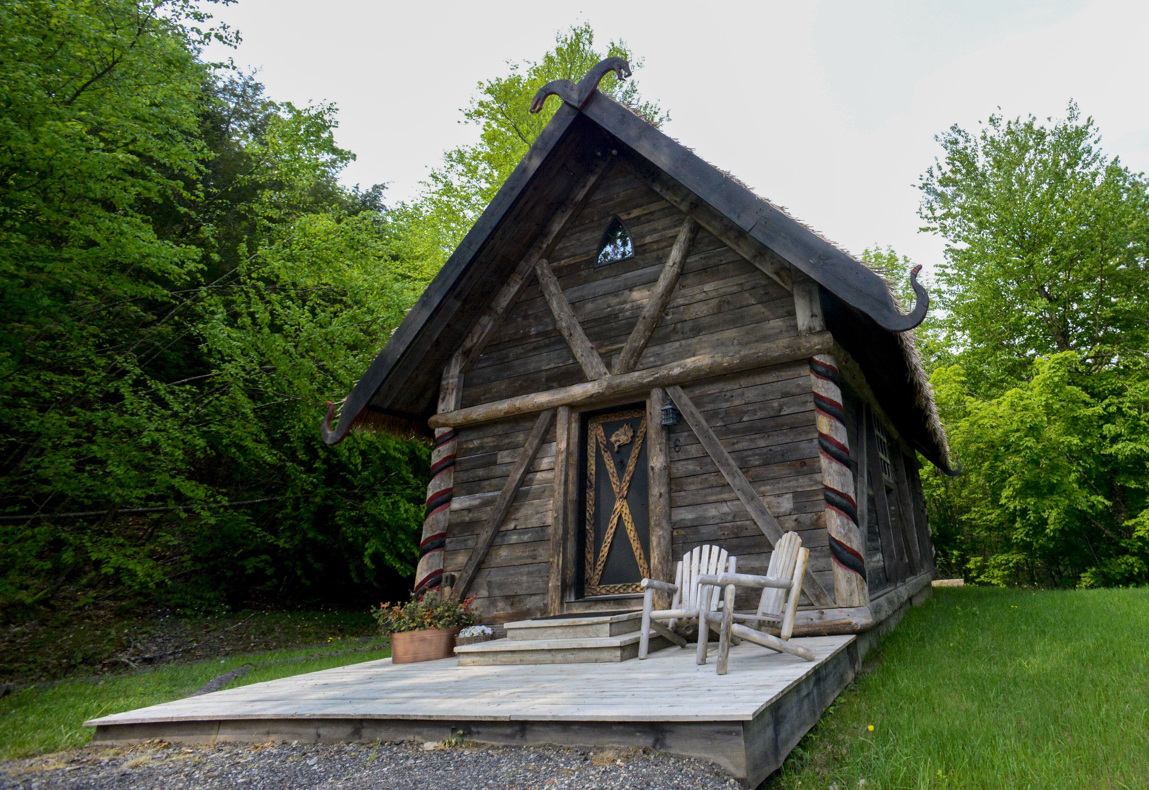 A rustic log cabin with a wooden porch and two Adirondack chairs.