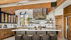 Una cocina moderna con una isla grande, armarios de madera y una chimenea de piedra.