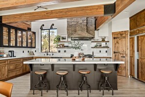 A modern kitchen with a large island, wooden cabinets, and bar stools. - Steel Pine Lodge · Steel Pine Lodge A Rustic Mountain Retreat Views! (Big Bear)