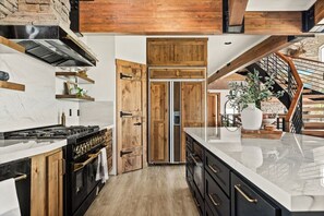 A modern kitchen with a central island, wooden cabinets, and a stone wall.