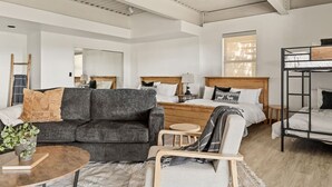 Una habitación de hotel moderna con sofá, cama, una mesita redonda y una litera.