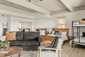 A modern hotel room with a sofa, a bed, a small round table, and a bunk bed.