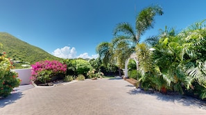 A paved pathway leading to a white structure, surrounded by lush greenery and a mountain in the background. - ORIENT BAY - 6-Bedroom - Amazing Ocean View - Sunseeker SXM (SAINT MARTIN)